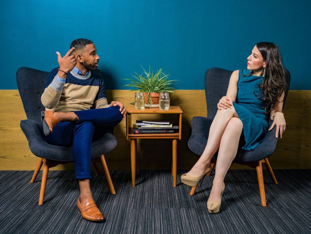 Woman talking, Wearing Teal Dress Sitting on Chair Talking to Man