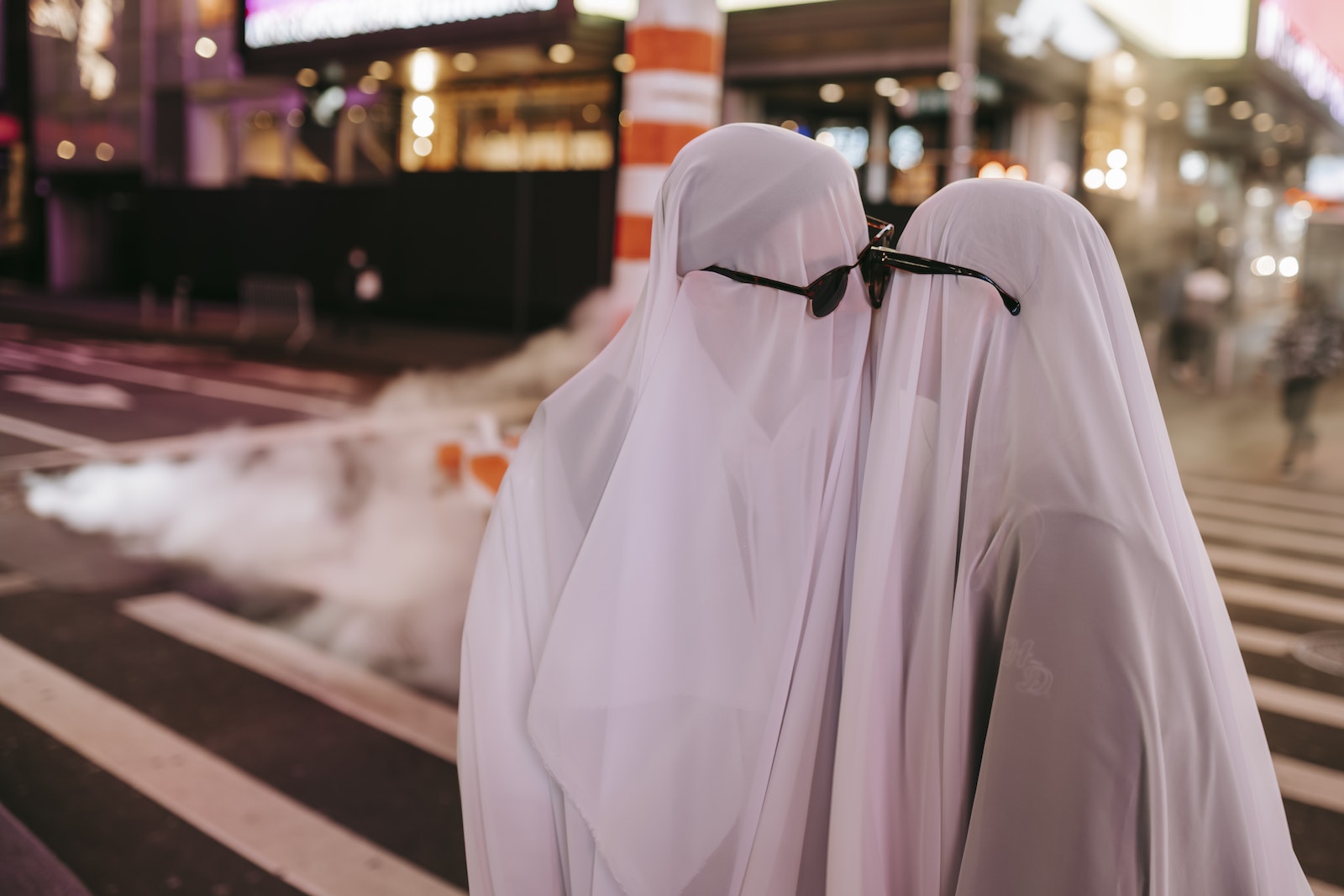 Unrecognizable couple in ghost costumes kissing on street