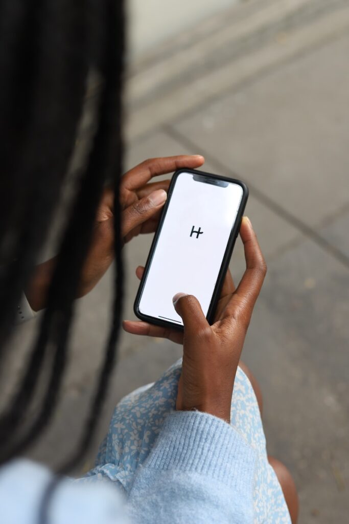 a woman holding a cell phone with a h on the screen