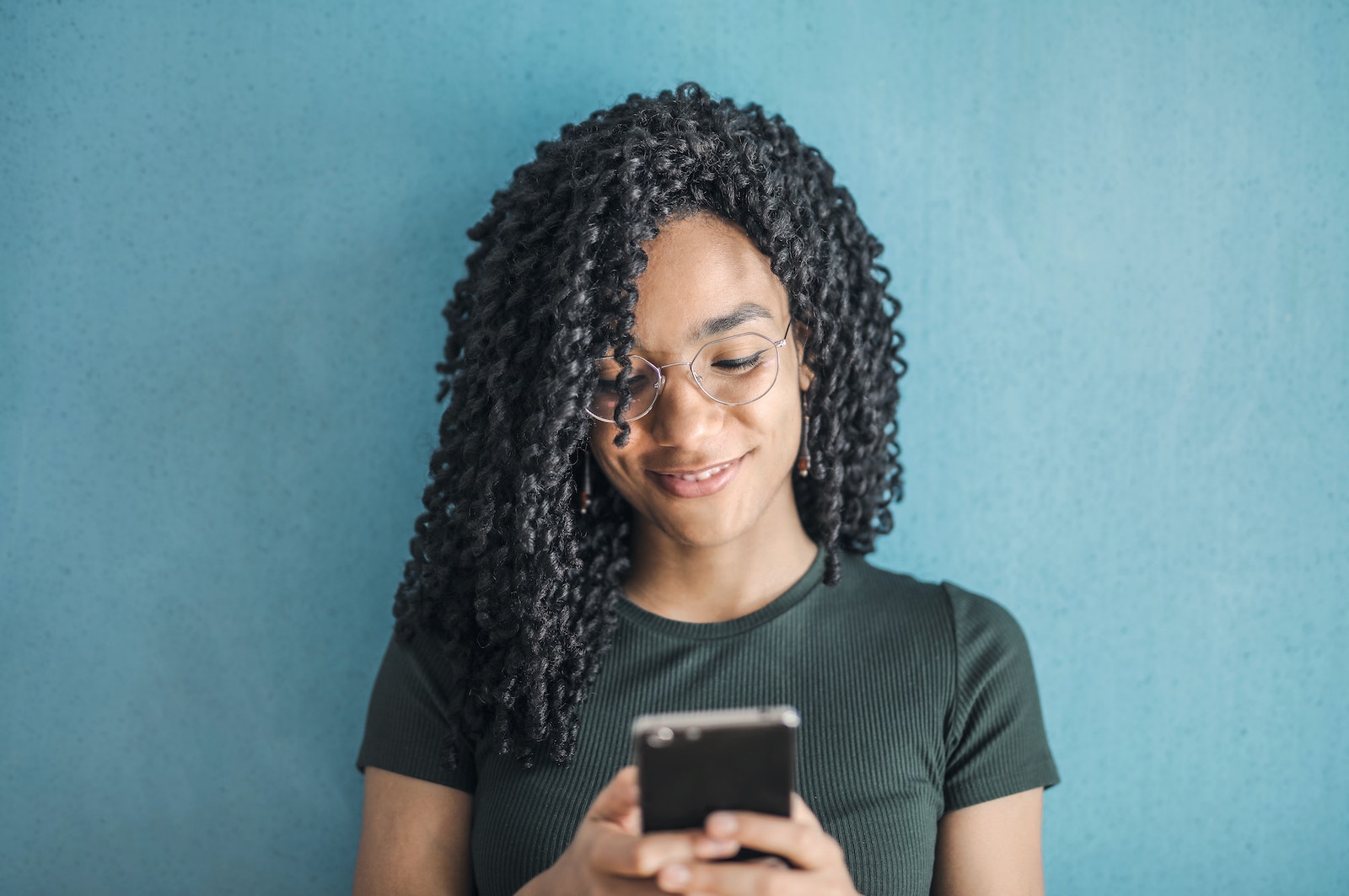 Portrait Photo of Smiling Woman in Black T-shirt and Glasses Using Her Smartphone