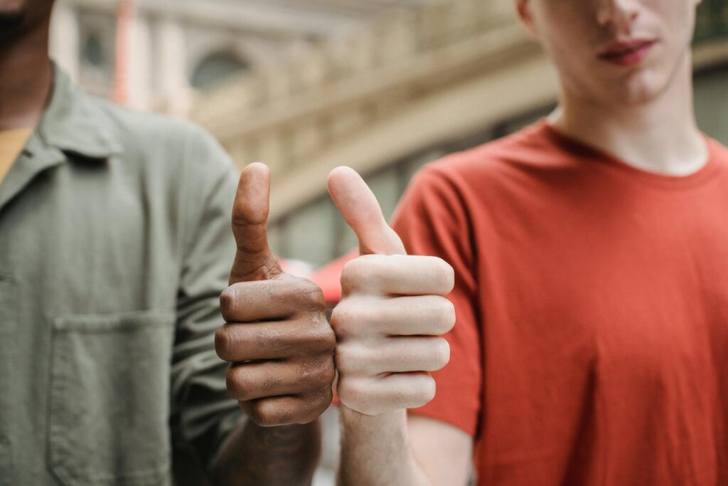 Unrecognizable multiracial guys showing thumbs up gesture