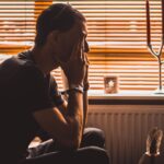 man sitting on chair covering his eyes