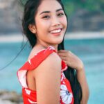 woman wearing white and red floral top across body of water